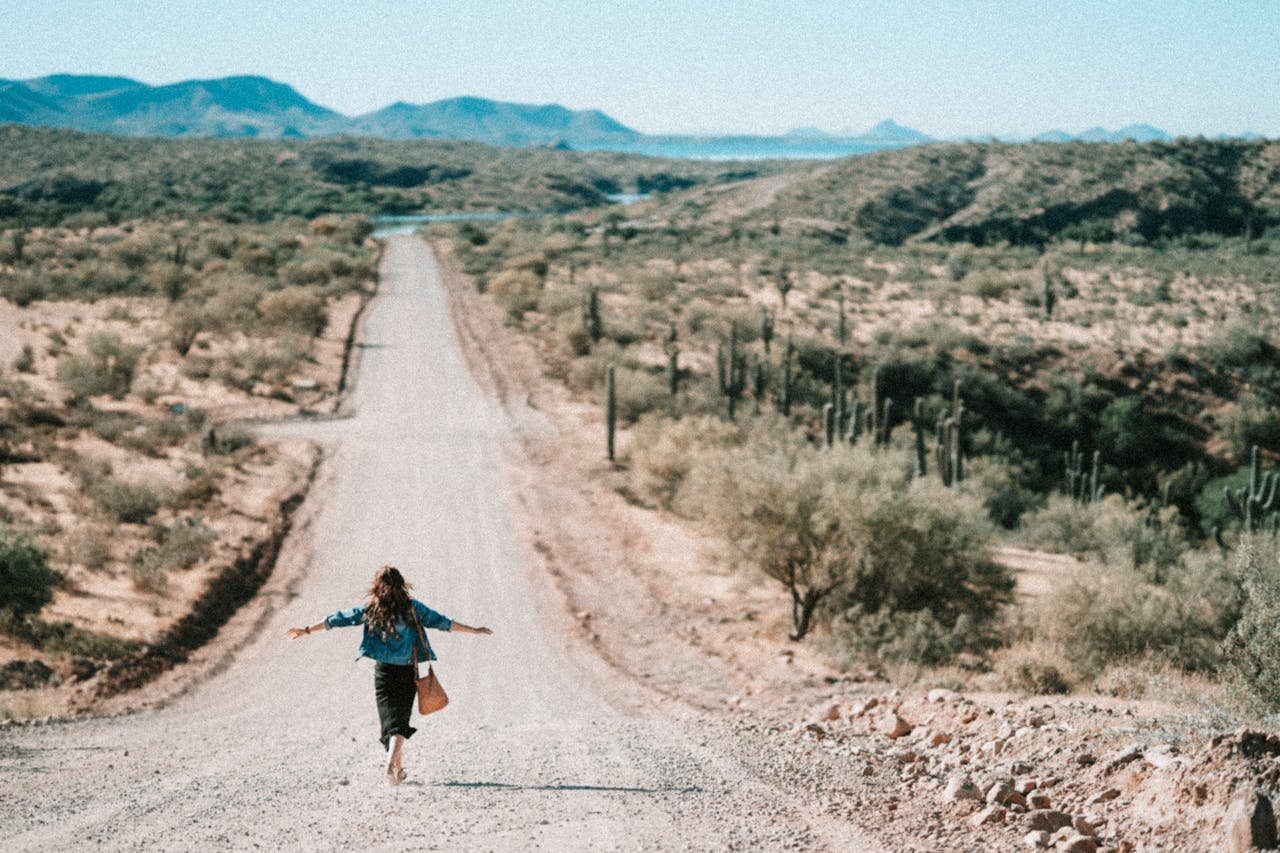 why-choose-us A woman walks freely down a winding desert road in Arizona, embracing adventure.